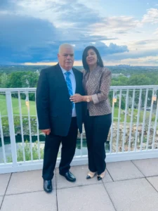 A man and woman stand on a balcony, overlooking a vibrant city skyline in the background